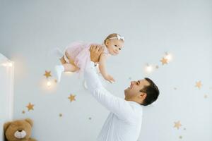 père levage bébé fille. content père choix en haut et jette le sien levage une petit enfant. Accueil atmosphère, content famille en riant bébé photo