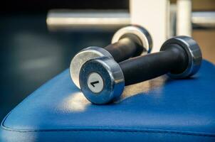 haltère, haltère dans le Gym sur une bleu Contexte. Gym pour aptitude. exercice équipement dans le salle de sport. photo