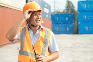 entretien ouvrier travail avec cargaison conteneurs. ingénieur dans sécurité casque, réfléchissant gilet, en portant walkie talkie avec récipient exportation et importer affaires et logistique Contexte. photo