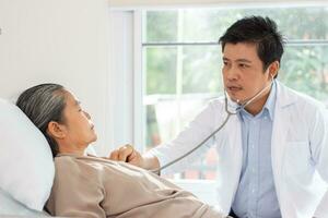 Masculin médecin discuter plus de médical record avec Sénior femme dans hôpital. photo