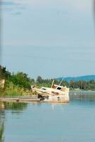 vieux rouillé bateau échoué sur le rive de le rivière baie. Humain la pollution par industriel déchets. verticale vue photo