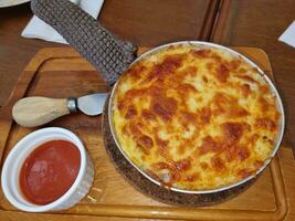 lasagne chaud gril dans cercle la poêle sur en bois assiette servir avec tomate sauce. fait maison Pâtisserie cuisine dîner photo