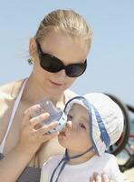 Jeune mère alimentation sa fils à le plage. photo