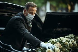 une homme dans une noir costume et blanc gants charges une cercueil dans une funéraire voiture photo