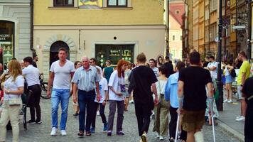 Varsovie, Pologne. 29 juillet 2023. foule de gens en marchant sur une rue. une foule en mouvement contre une Contexte de un Urbain vieux ville paysage. photo