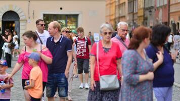 Varsovie, Pologne. 29 juillet 2023. foule de gens en marchant sur une rue. une foule en mouvement contre une Contexte de un Urbain vieux ville paysage. photo