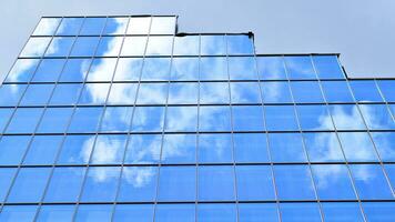 de construction verre mur reflétant bleu ciel. abstrait moderne architecture fragment. verre bâtiment avec transparent façade de le bâtiment et bleu ciel. contemporain architectural Contexte. photo