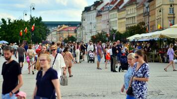 Varsovie, Pologne. 29 juillet 2023. foule de gens en marchant sur une rue. une foule en mouvement contre une Contexte de un Urbain vieux ville paysage. photo