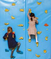 petite fille escaladant un mur de roche à l'intérieur photo