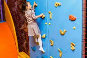 petite fille escaladant un mur de roche à l'intérieur photo