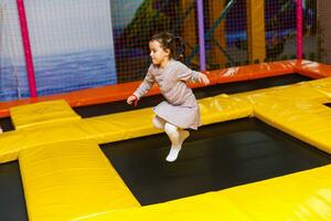 peu jolie fille est ayant amusement Extérieur. en jouant dans les enfants zone dans amusement parc. photo