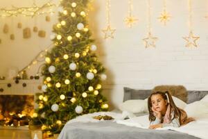 peu fille mensonges sur une lit dans une pièce décoré pour Noël photo