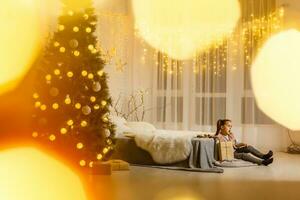 le fille séance dans le pièce avec une content Noël atmosphère. photo