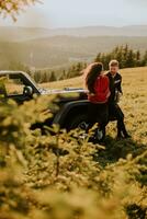 jeune couple se reposant près d'un capot de véhicule tout-terrain à la campagne photo