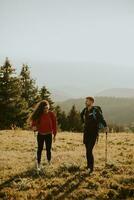 Couple souriant marchant avec des sacs à dos sur les collines verdoyantes photo