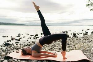 formation dans nature, améliore pilates et élongation. sur de soi et harmonie dans une en bonne santé Humain corps. le entraîneur Faire le yoga asana exercer, les usages une tapis. photo