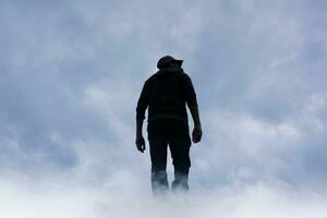 homme silhouette parmi des nuages dans le Montagne photo