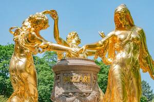 Dresde, Allemagne - d'or monument pour Mozart dans le citoyenne Prairie parc appelé burgerwiese. paysage urbain de le centre ville à ensoleillé printemps journée et bleu ciel. photo