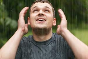 Jeune homme en dessous de le pluie. photo