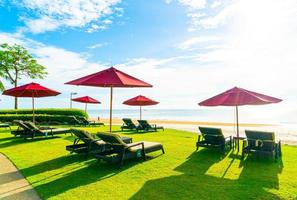 parasols rouges et chaises de plage avec fond de plage de mer et ciel bleu et soleil photo