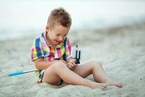 content garçon avec selfie bâton et cellule à le bord de mer photo