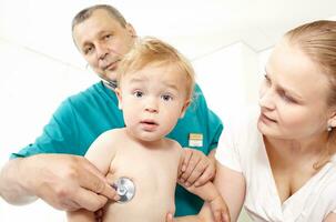 médecin Ecoutez le bébé garçon avec stéthoscope. photo