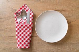 assiette ou plat vide avec couteau, fourchette et cuillère sur fond de carreaux de bois photo