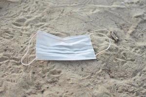 masque usagé pendant covid 19 a été jeté sur la plage de sable. le sujet est ébavuré.