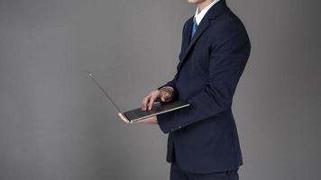 homme d'affaires utilise un ordinateur portable, fond gris en studio photo