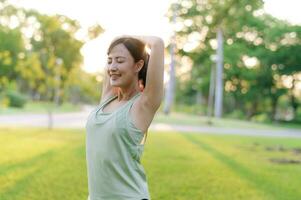 femelle joggeur. en forme Jeune asiatique femme avec vert tenue de sport élongation muscle dans parc avant fonctionnement et profiter une en bonne santé Extérieur. aptitude coureur fille dans Publique parc. bien-être étant concept photo