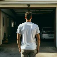 ai génératif une homme portant une plaine blanc t - chemise sur le garage orienté vers en arrière, parfait à créer T-shirt maquette photo