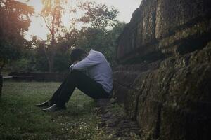 Asie vous homme séance seul.il séance seul à côté de vieux mur.homme très triste et déprimé.triste,seul,suicide,désespoir,maladie,photo santé et déception concept. photo