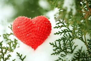 crocheté rouge coton cœur dans le neige sur une arbre dans l'hiver. photo