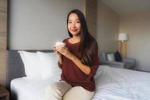 Portrait de belles jeunes femmes asiatiques avec une tasse de café sur le lit