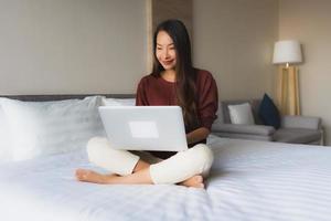 portrait de belles jeunes femmes asiatiques utilisant un ordinateur et un téléphone portable sur le lit photo