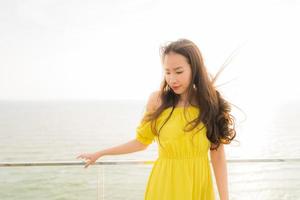 portrait belle jeune femme asiatique sourire heureux et se détendre au balcon extérieur avec vue sur la plage et l'océan photo