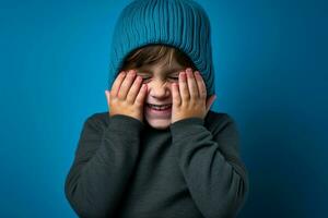une garçon avec une bleu tricoté chapeau est en riant sur Contexte photo