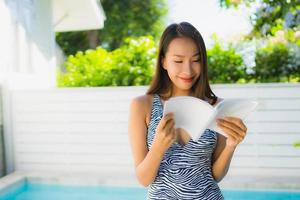 Portrait belle jeune femme asiatique sourire heureux avec livre de lecture autour de la piscine photo