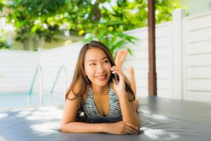 Portrait belle jeune femme asiatique sourire heureux parler téléphone portable autour de la piscine photo