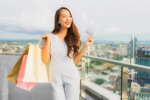 Portrait belle jeune femme asiatique heureuse et souriante avec carte de crédit pour sac à provisions du grand magasin photo