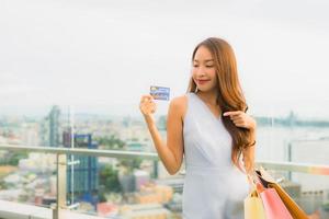 Portrait belle jeune femme asiatique heureuse et souriante avec carte de crédit pour sac à provisions du grand magasin photo