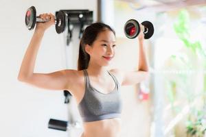 Portrait belle jeune femme asiatique exercice avec équipement de fitness à l'intérieur de la salle de sport photo