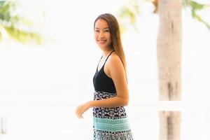 Portrait belle jeune femme asiatique heureuse et souriante avec voyage dans un complexe hôtelier près de la mer et de la plage photo