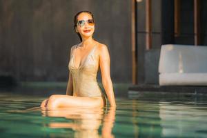 Portrait jeune belle femme asiatique sourire heureux et se détendre dans la piscine autour de l'hôtel resort photo