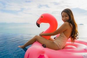 Portrait young asian woman on flamingo flotteur gonflable autour de la piscine extérieure de l'hôtel resort photo