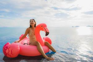 Portrait young asian woman on flamingo flotteur gonflable autour de la piscine extérieure de l'hôtel resort photo