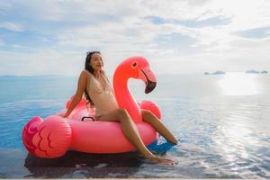 Portrait young asian woman on flamingo flotteur gonflable autour de la piscine extérieure de l'hôtel resort photo