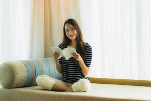 Portrait belle jeune femme asiatique lisant un livre sur un canapé dans le salon photo