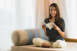 Portrait belle jeune femme asiatique lisant un livre sur un canapé dans le salon photo