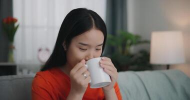 asiatique femme en buvant une café tandis que séance sur le canapé photo